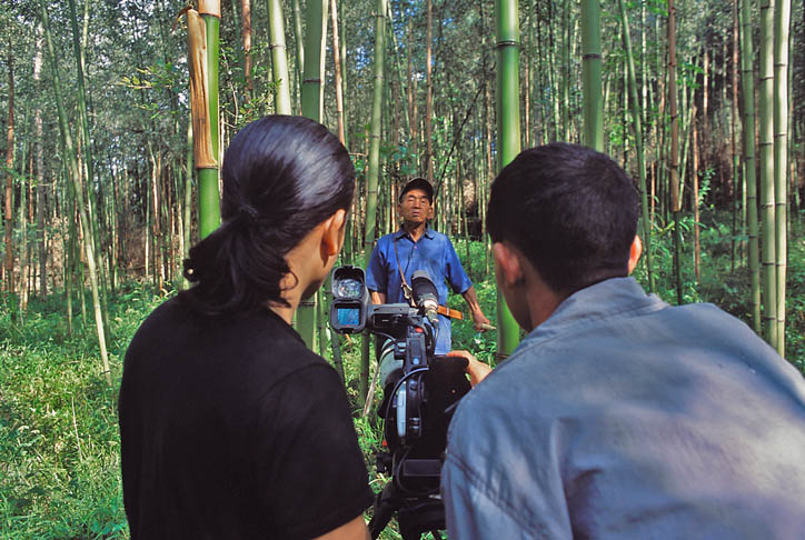 Hage Komo gets video instructions from Moji Riba, who is enlisting local young people to capture the oral histories, languages and rituals of their tribes for his project. Komo films his father gathering bamboo in a grove outside Hari Village. (Photo courtesy Rolex Awards)