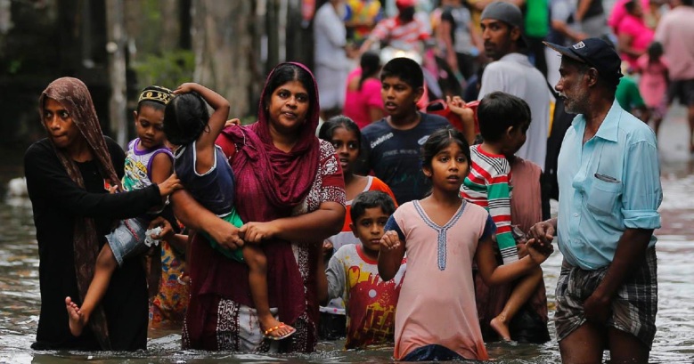 Sri Lankans wade through a road submerged in flood waters in Colombo, 18 May 2016 (Photo by Eranga Jayawardena, AP)